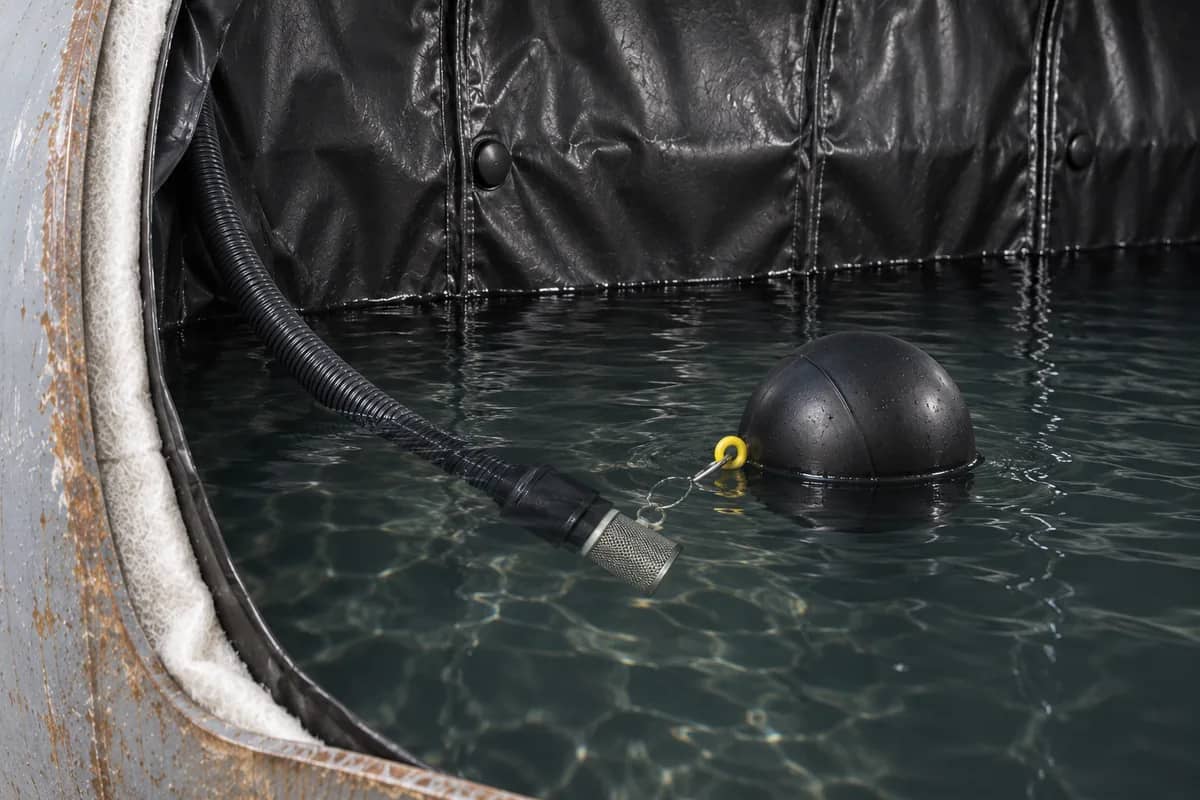 KI-Prinzipdarstellung: Schwimmkörper hält eine Ansauggarnitur unter der Wasseroberfläche eines ausgekleideten Tanks.